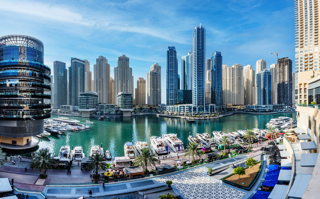 Dubai Marina Skyline mit Yachthafen, modernen Hochhäusern und Waterfront-Promenade bei klarem Himmel.